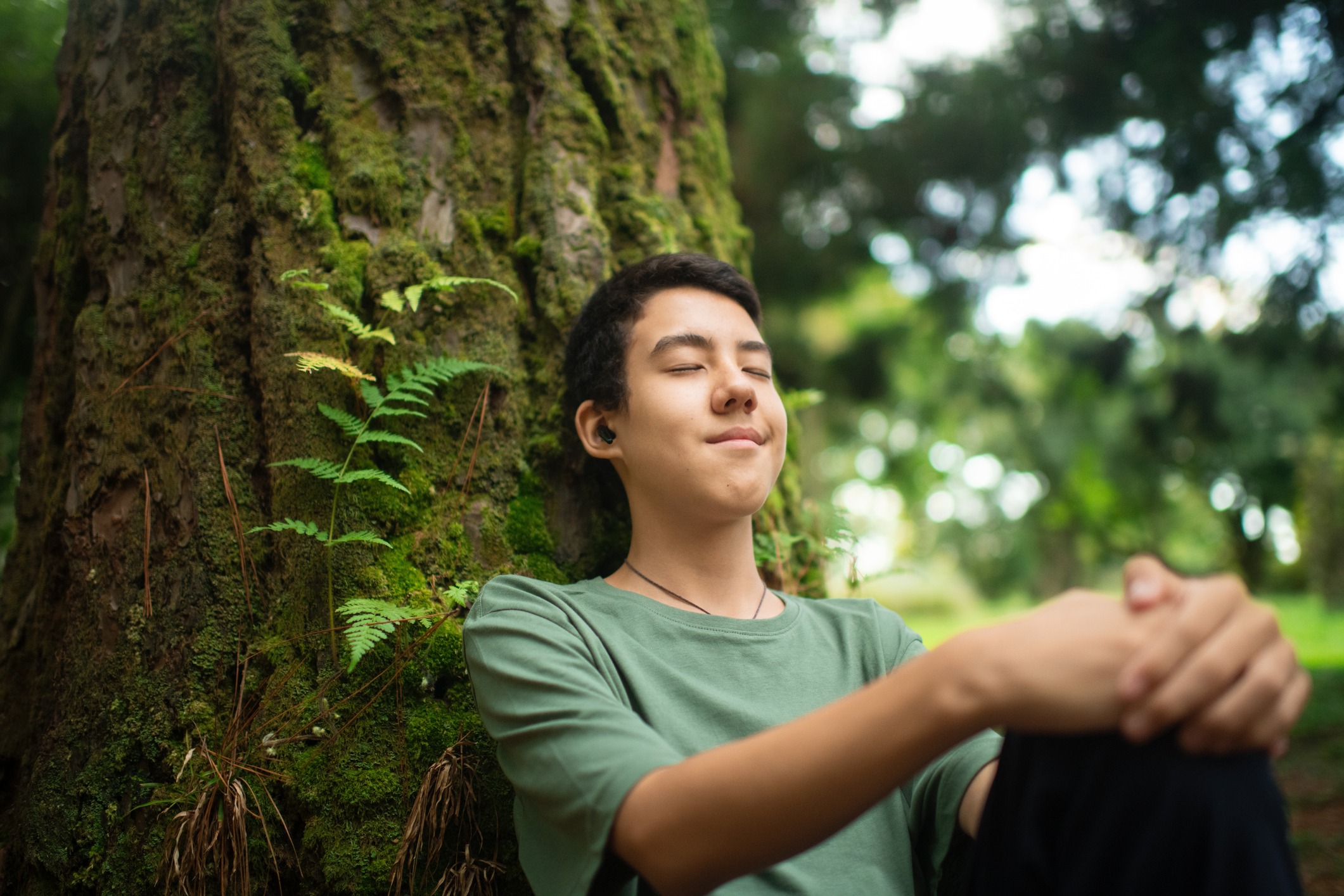 Teenage boy listening to music in a park in summer
